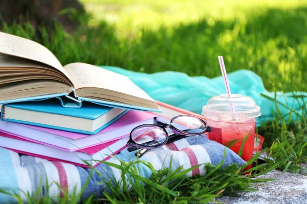 picture of books, glasses and towel in the grass